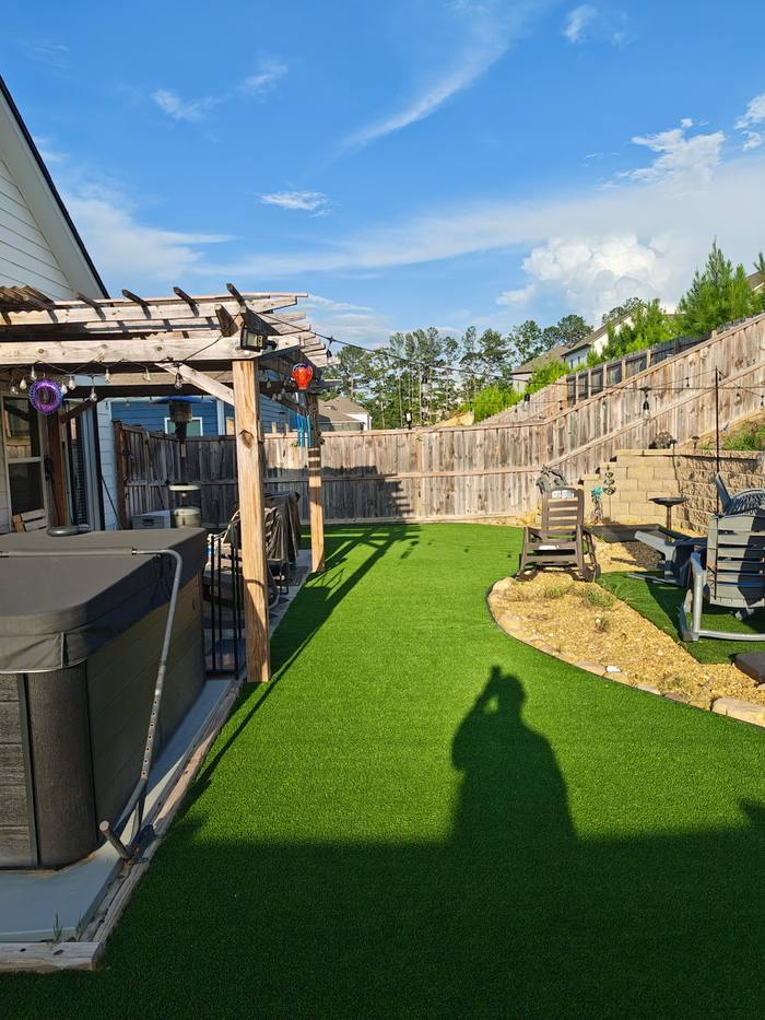 Sloped backyard turf with pergola and hot tub